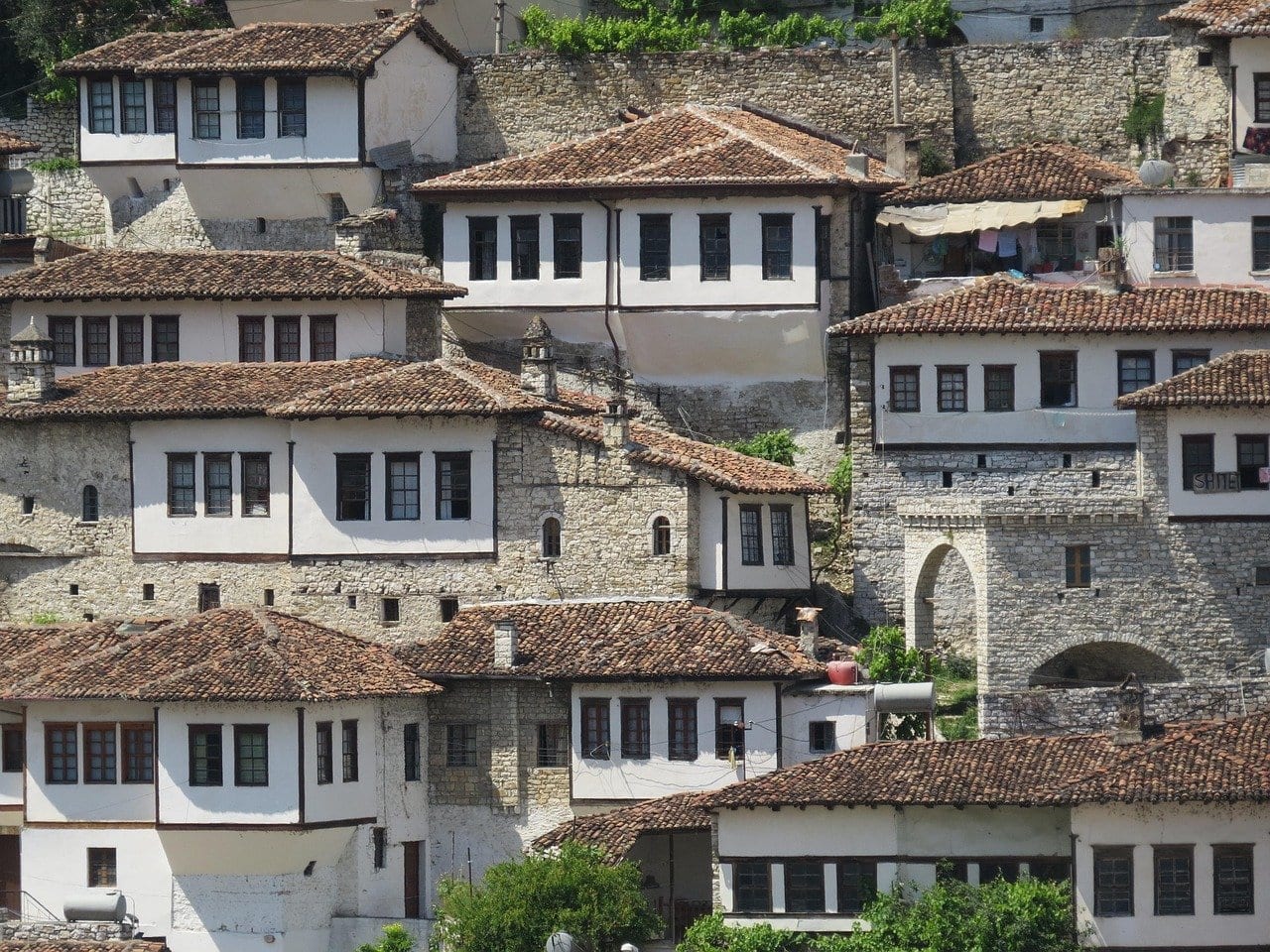 Weiß verputzte Häuser mit vielen Fenstern und Ziegeldächern, die in Reihen übereinander an einem Hang in Berat stehen