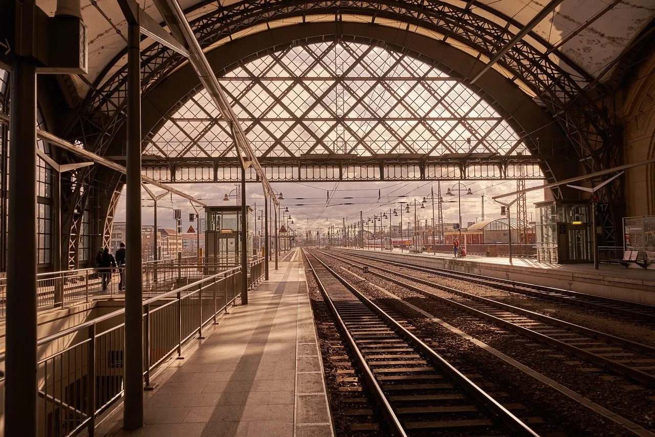 Bahnsteighalle des Dresdner Hauptbahnhofs mit Glasdach und Stahlbögen, daneben mehrere Gleise, die in die Ferne führen