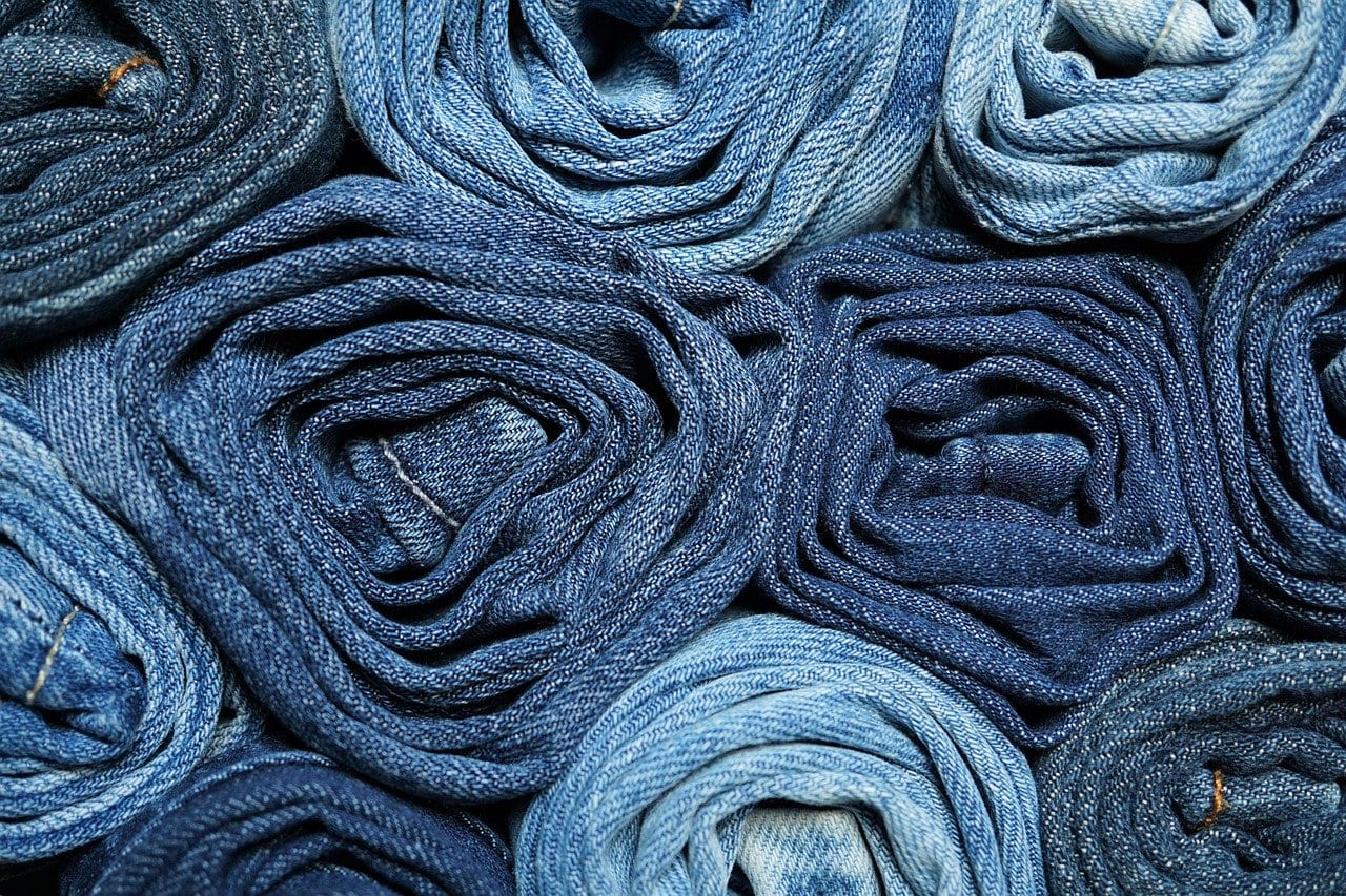 Mehrere eng gerollte Jeans in verschiedenen Blautönen, dicht nebeneinander gestapelt