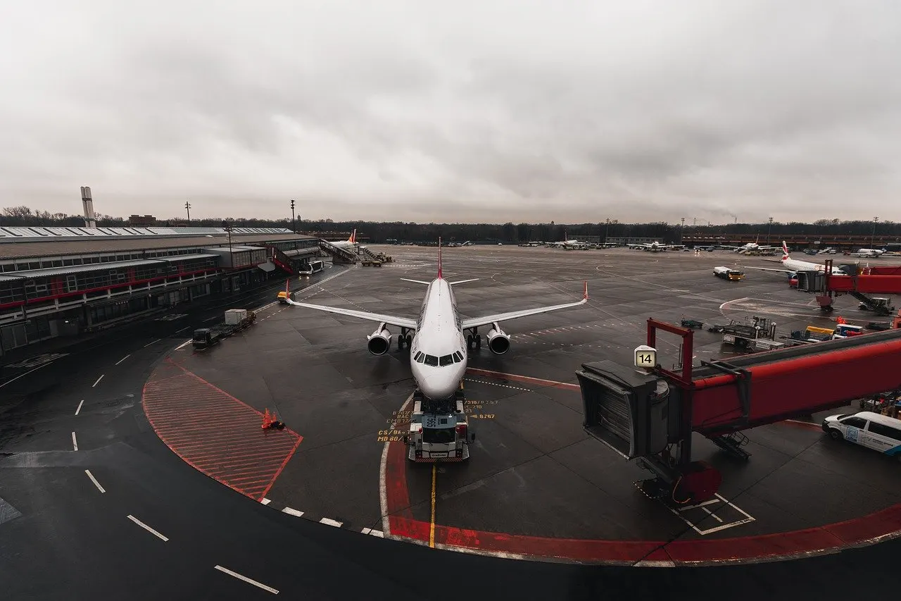 Passagierflugzeug mit Schlepper an der Parkposition 14 neben einer Fluggastbrücke, Vorfeld eines Flughafens bei bewölktem Himmel